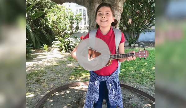 Picture of a young girl outside playing a ukulele