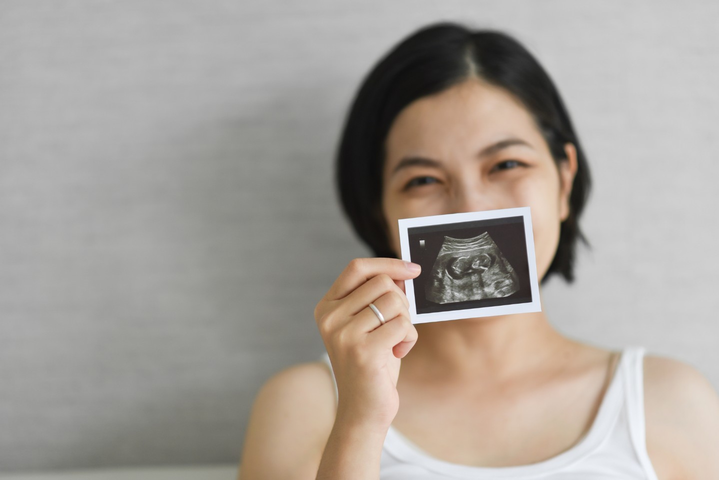 Asian mother holding up an ultrasound photo
