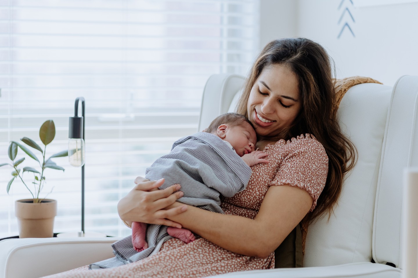 Mother holding newborn baby in a plush chair