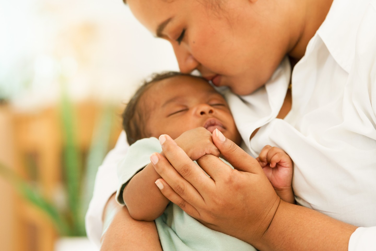 Mother nuzzling top of newborn baby's head