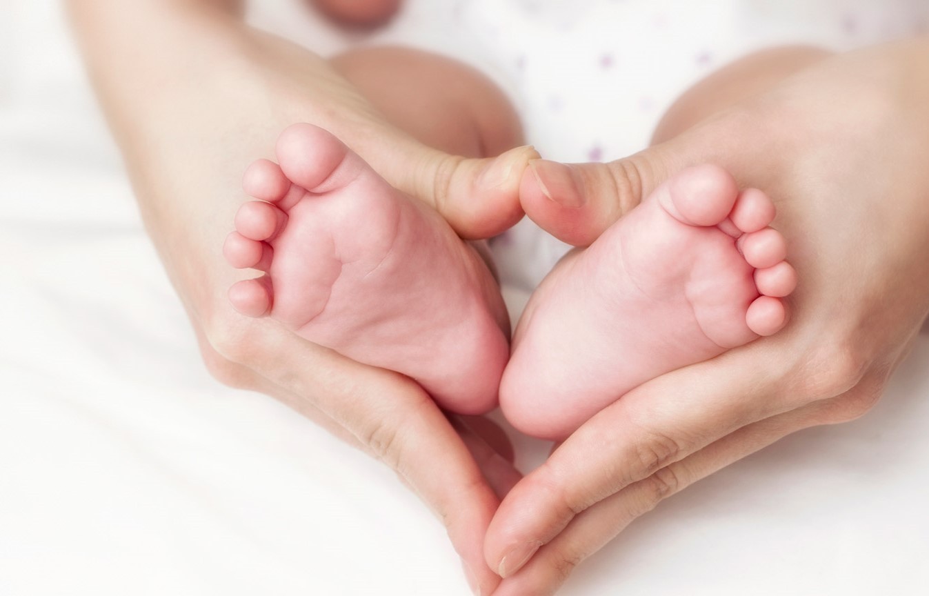 tiny baby's feet in moms heart-shaped hands