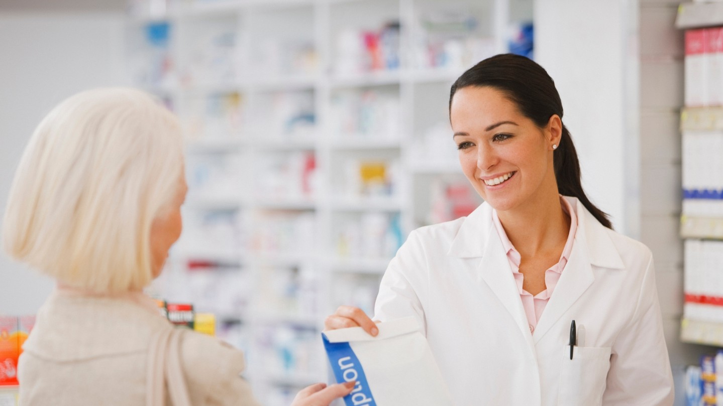 friendly pharmacist giving prescriptions to customer