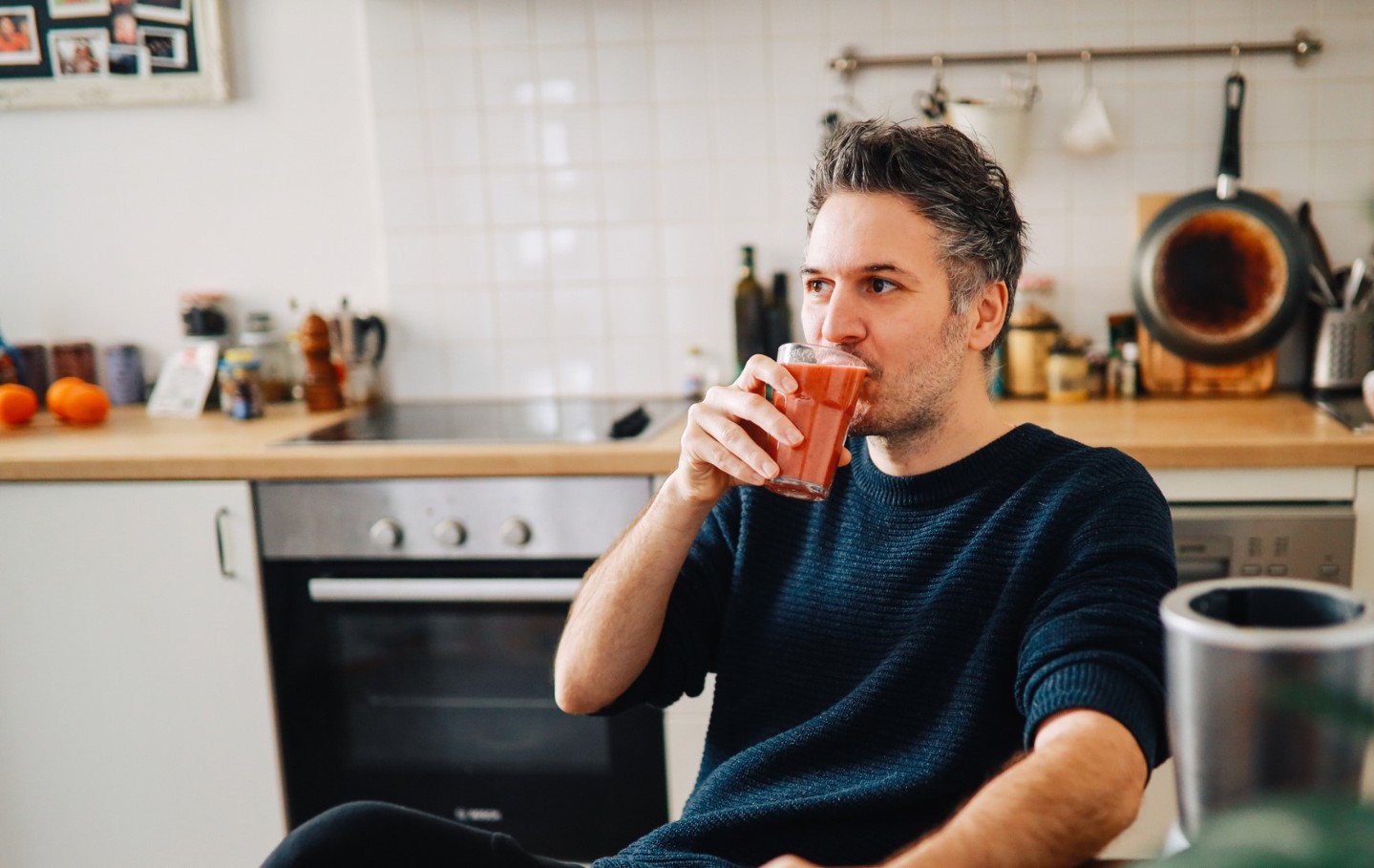 Man drinking a smoothie in his kitchen
